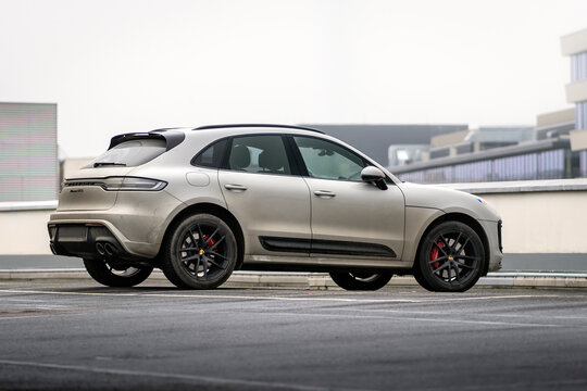 Gray Porsche Macan sports SUV parked on the roof of a department store. Dirty luxury car outside in a parking lot.