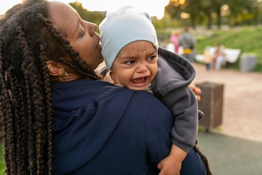 Woman comforting crying baby in outdoor park