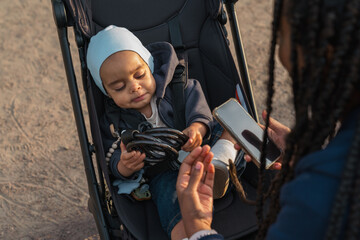  Baby in stroller holding a cable with mother showing a phone
