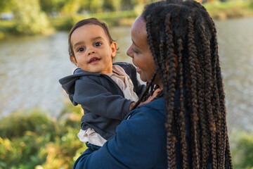 Smiling Mother Holding Happy Baby by a Riverside