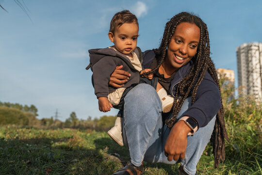 Smiling woman holding baby outdoors on a sunny day