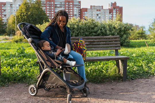 Mother and child sitting by a bench with a stroller in a park