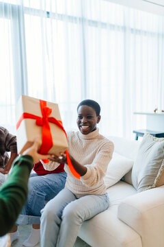 Young woman receiving wrapped Christmas gift