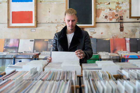 Young man browsing vinyl records in a second hand record store