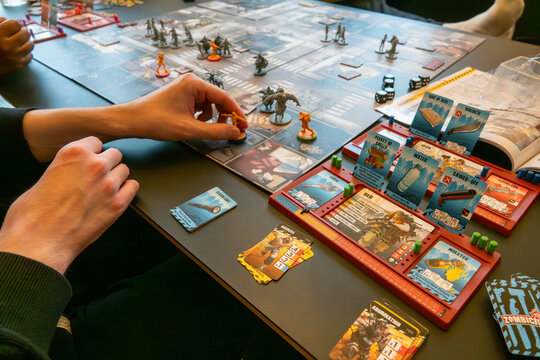 Hands of people playing the popular adventure board game zombicide. Copenhagen, Denmark - November 22, 2024.
