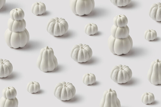 Creative white painted pumpkins on plain studio background