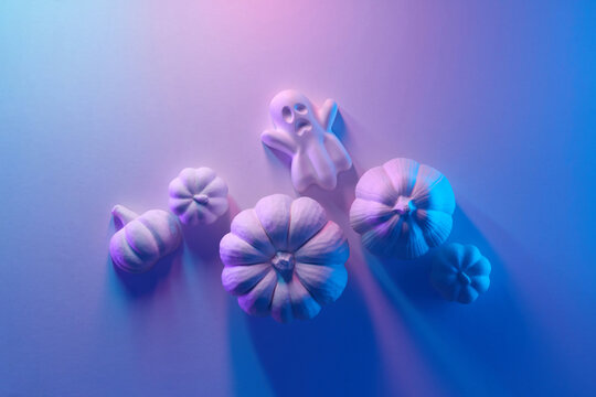 Ghost figure with white pumpkins in neon pastel light
