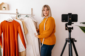 Confident seamstress recording video in fashion atelier