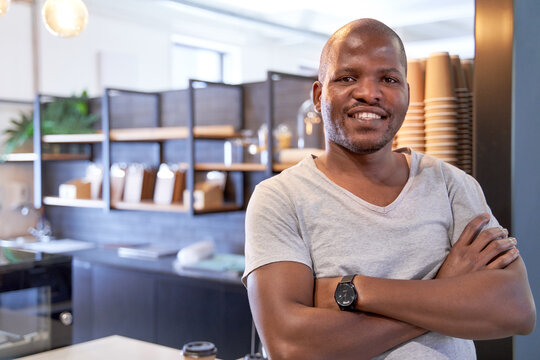 Attractive, charming young African American male entrepreneur in coworking space coffee shop counter smiling confidently