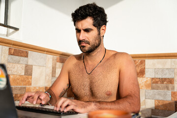 Freelancer working from home on laptop without a shirt