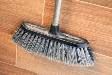 Dirty broom on wooden floor