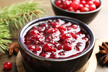 Tasty cranberry sauce in bowl on wooden table, closeup