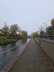 Bürgersteig mit dem Havelfluss auf der linken Seite in Brandenburg an der Havel, an einem atmosphärischen Herbsttag