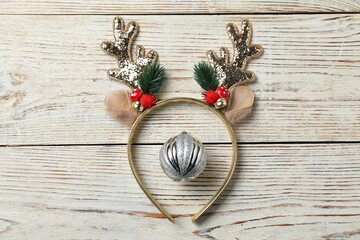 Beautiful reindeer headband and Christmas bauble on white wooden background, top view