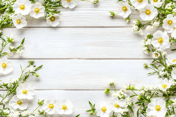 Fototapeta premium White flowers arranged on a rustic white wood background, creating a beautiful floral frame with copy space. Perfect for springtime, wedding, or feminine designs.