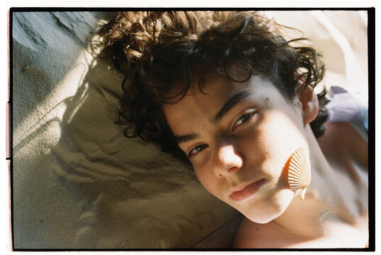 A Young Person Relaxing With a Shell by the Shore