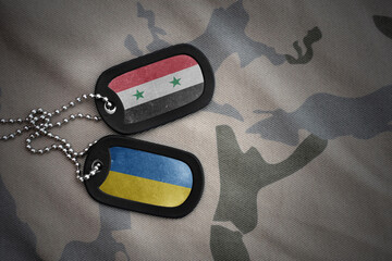 army blank, dog tag with national flag of syria and ukraine on the khaki texture background....