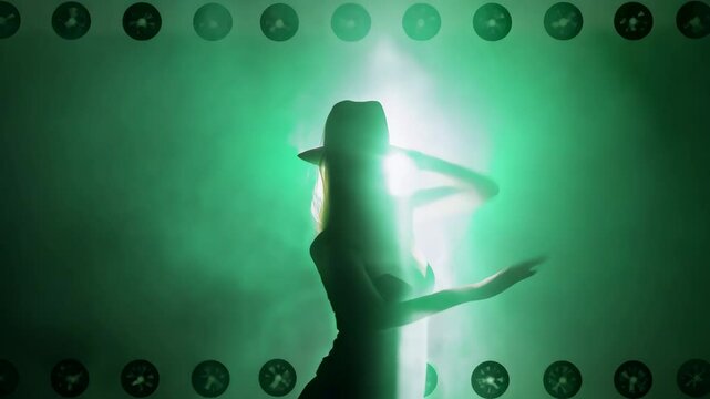 Silhouetted dancer emerges through ethereal green smoke against dramatic backlighting, dancing smoothly, hypnotical fluid moves. Stage fans create atmospheric effect. Mysterious theatrical setting.
