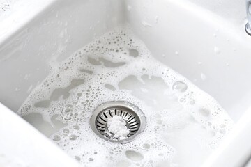 A sink filled with water and a faucet nearby, ideal for bathroom scenes or still life photography