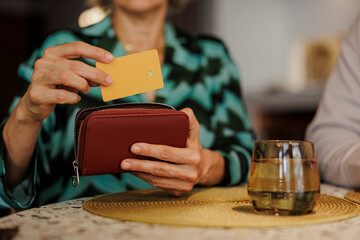 Woman taking credit card out of her wallet at restaurant table