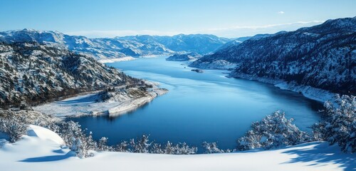 A wide river surrounded by snowy mountains, captured from a high-altitude perspective, showcasing the majestic winter landscape.