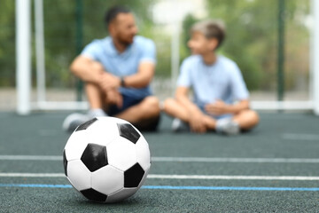 Father with his son and soccer ball on football field