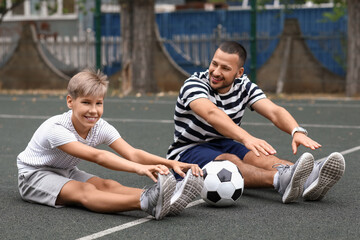 Father and son doing warm-up on soccer pitch