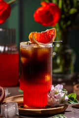 Refreshing espresso and blood orange cocktail with ice and flowers