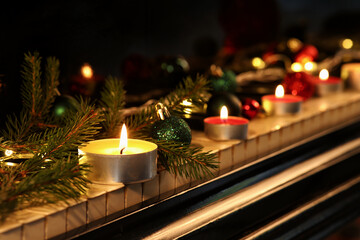 Piano keys with Christmas balls, glowing garland, burning candles and fir tree branches