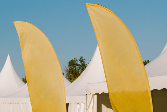 Yellow flags and a white tent against a blue sky