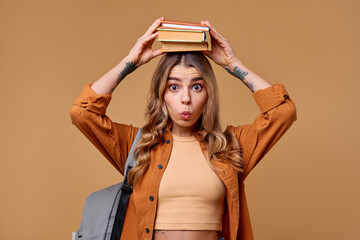 A student joyfully balancing multiple books while wearing a playful expression on her face