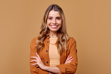 A smiling young woman stands confidently with arms crossed, looking stylish and relaxed