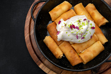 Fried pancakes with cottage cheese and sour cream on a wooden board
