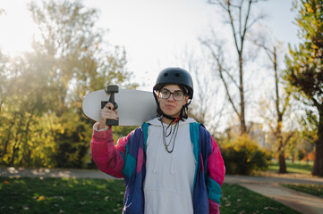 Young skater holding her skateboard in a park during a sunny day