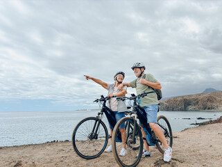 Two happy old mature people enjoying and riding bikes together to be fit and healthy outdoors....