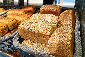 Freshly baked bread in wicker baskets. Variety of loaves in a bakery. Artisanal bread selection. Bread shop with handmade baked goods. Rustic bread display. Traditional baking background.