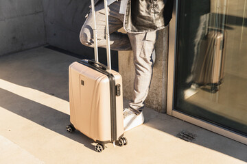 Casual Man with Suitcase Leaning Against Building