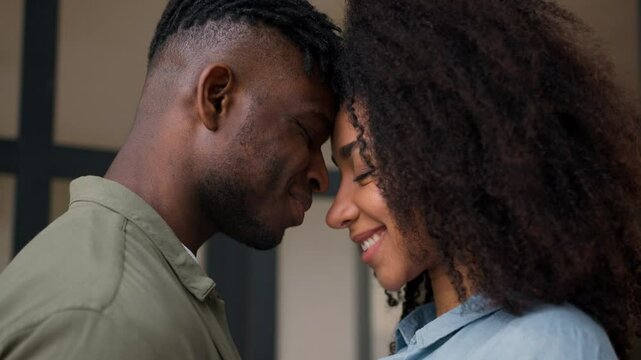 Affectionate couple African American happy family man woman at home love feelings touch foreheads bonding hugging wedding honeymoon girl guy male female husband wife closeness relationships smiling