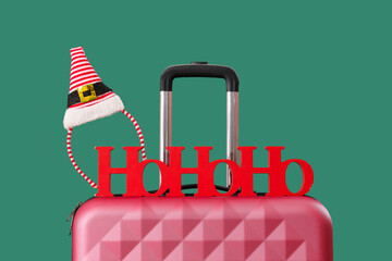Suitcases with lettering HOHOHO and elf hat on green background. Closeup