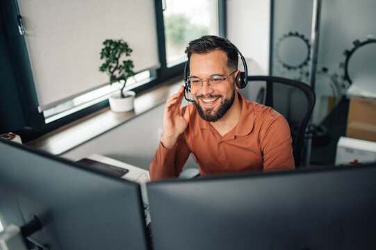 Smiling customer service representative working from home office using headset and dual monitors