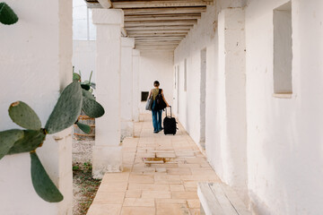 Female traveler walks with her luggage through corridors in a masseria
