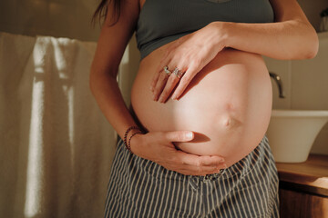 Close-up of Pregnant Woman Holding Her Belly in Soft Light