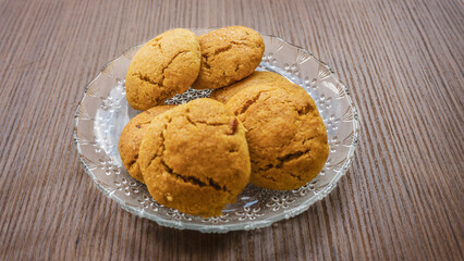A plate of freshly baked golden-brown cookies served on a glass dish.