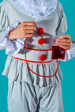 clown holds a fake blood bag in his hand