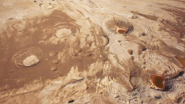 Aerial view of sinkholes near the Dead Sea, Israel. Captured by drone, the dramatic landscape reveals collapsed ground formations caused by the receding shoreline. A striking visual of environmental c