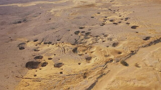 Aerial view of sinkholes near the Dead Sea, Israel. Captured by drone, the dramatic landscape reveals collapsed ground formations caused by the receding shoreline. A striking visual of environmental c