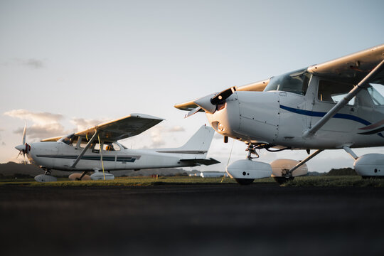 Two Single Engine Training Aircraft Parked On The Apron At Sunset.