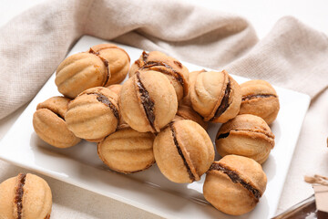 Plate with sweet walnut shaped cookies with boiled condensed milk on white background, closeup