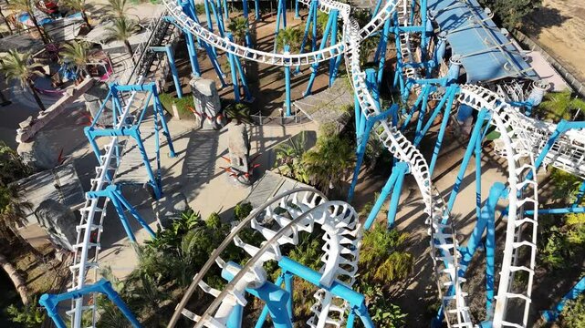 Aerial view of a vibrant amusement park featuring a roller coaster, Ferris wheel, and various attractions. Captured by drone, this colorful and dynamic scene showcases the excitement and energy