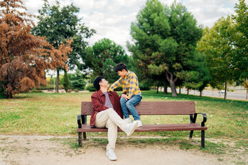Father and son sitting on a park bench enjoying time together